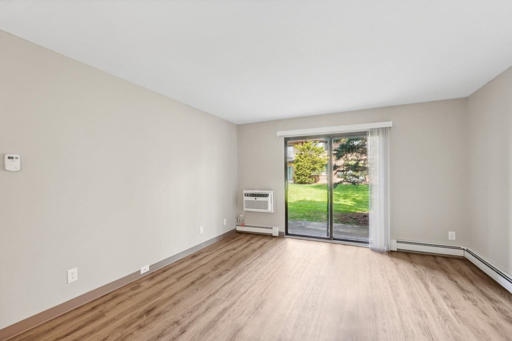 the living room of an empty house with wood flooring and a sliding glass door