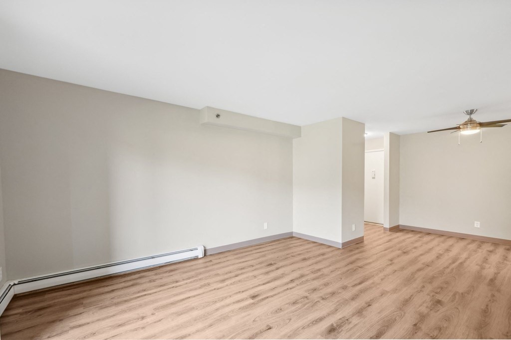 an empty living room with wood flooring and white walls