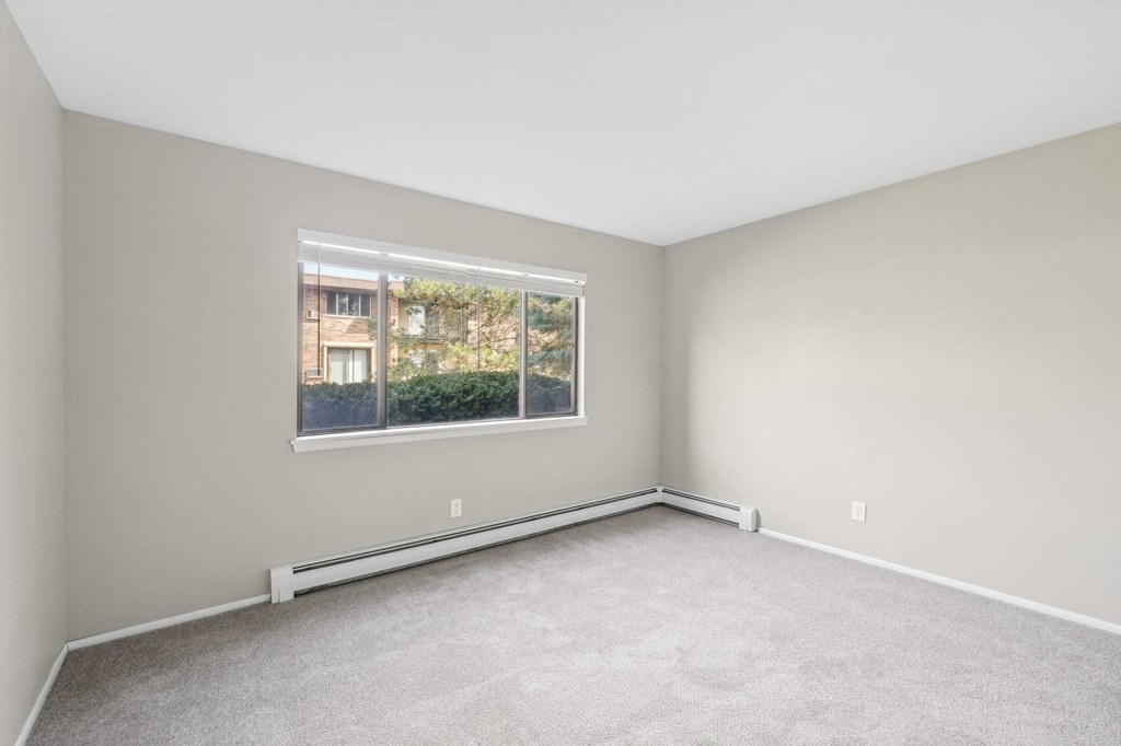 an empty bedroom with a large window and carpeting