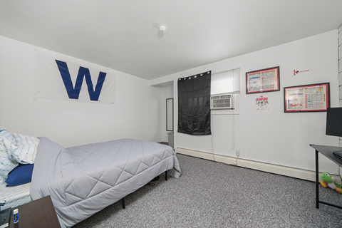 A bedroom with a bed, desk, and a wall with a letter W on it.