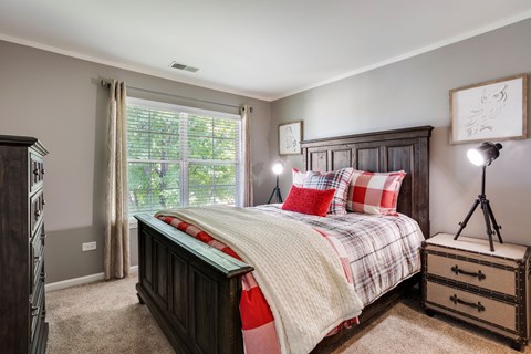 A bedroom with a large bed and a wooden dresser.