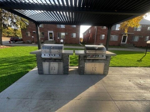 Two grills are on a patio in front of a building.