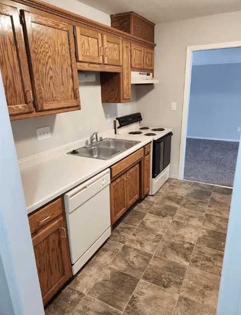A kitchen with wooden cabinets and a tiled floor.