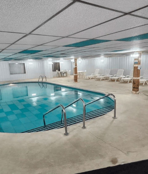 A large indoor swimming pool with a blue tiled edge and a metal ladder.