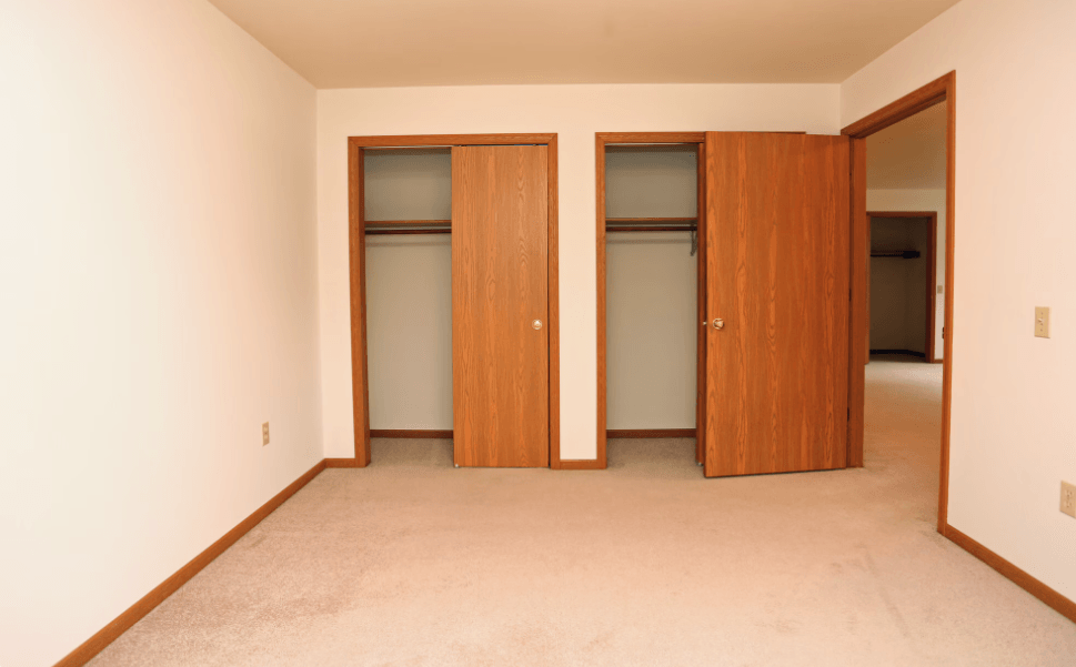 Two brown doors in a room with carpet.