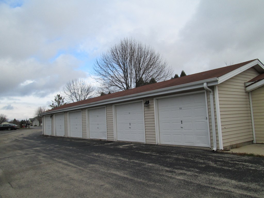 a row of three car garages with white doors and a red roof