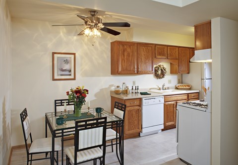 A kitchen with a table and chairs and a fridge.