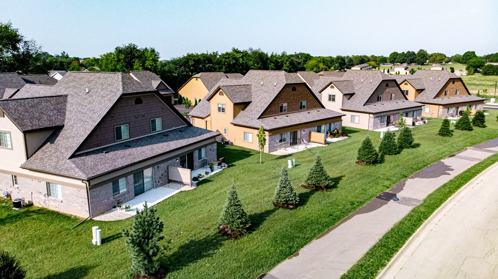 A row of houses with green lawns and trees in front.