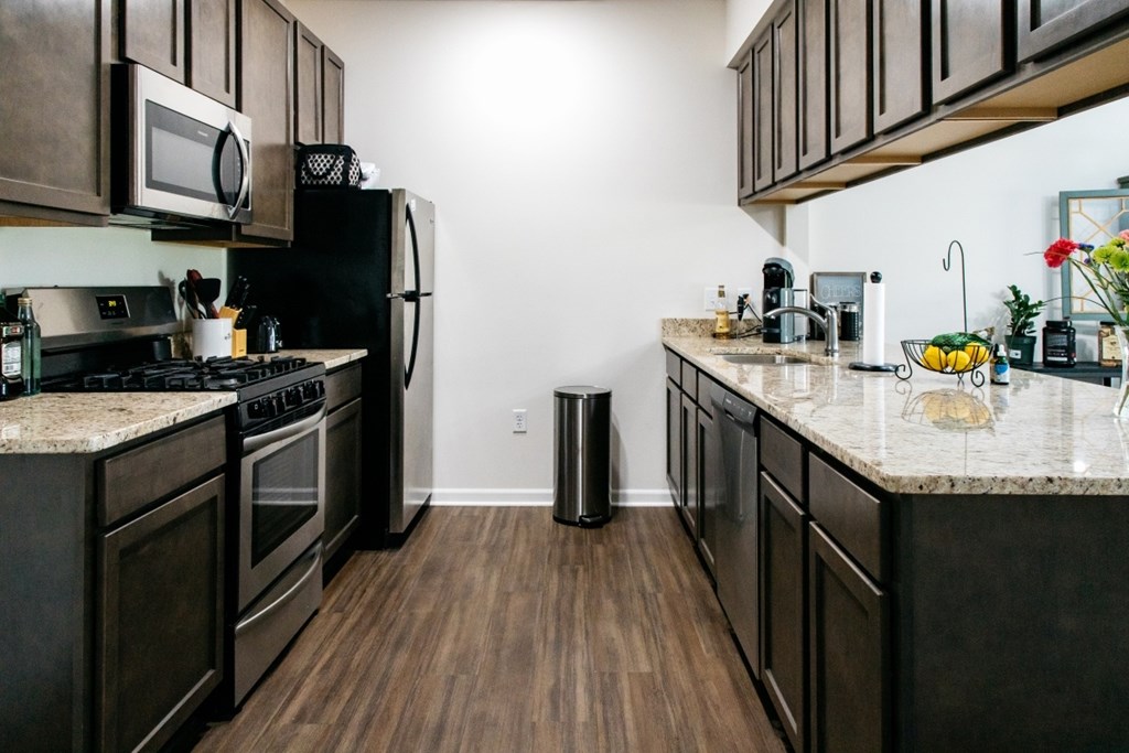 A kitchen with dark wood cabinets and a granite countertop.