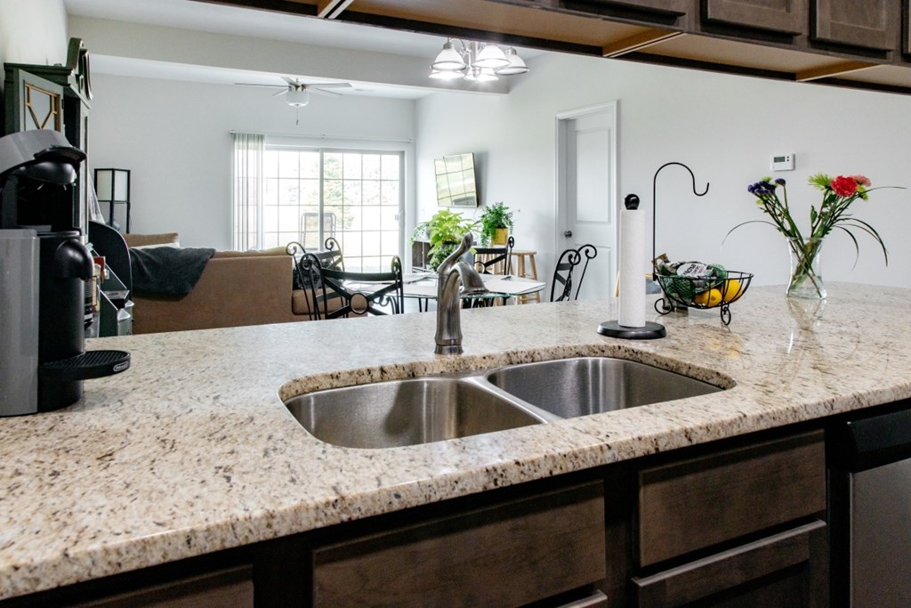 A kitchen with a granite countertop and a stainless steel sink.