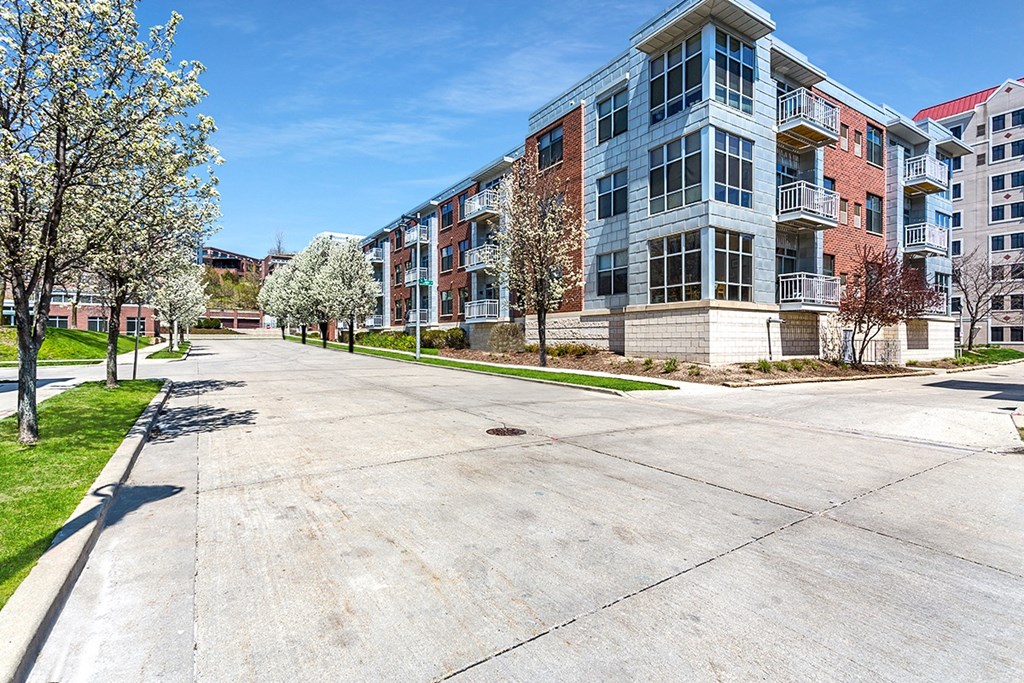 an empty street in front of an apartment building with trees