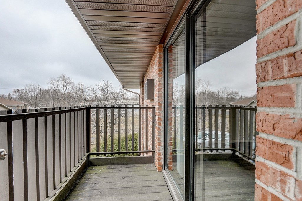 a balcony with a wooden deck and a brick wall