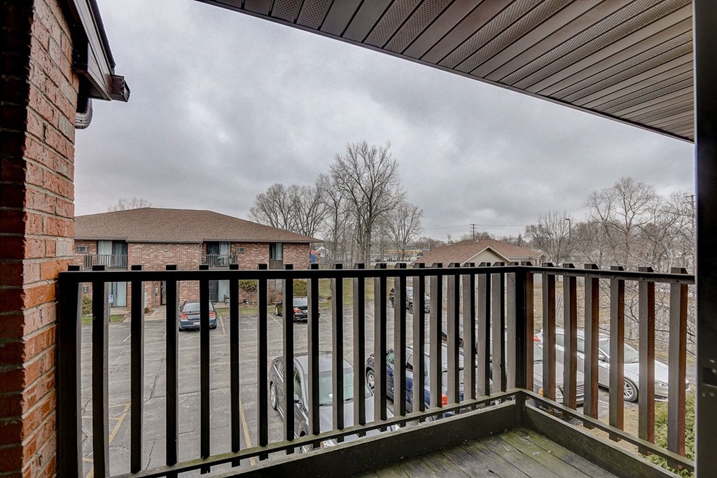 the balcony has a view of the parking lot and the house