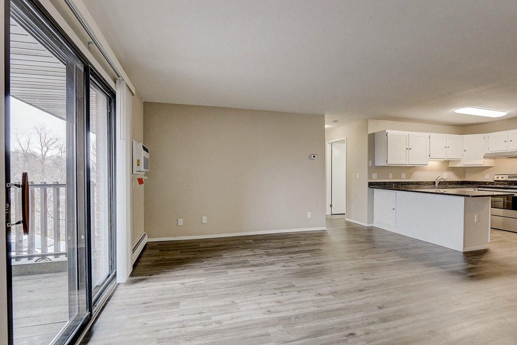 an empty living room and kitchen with a sliding glass door