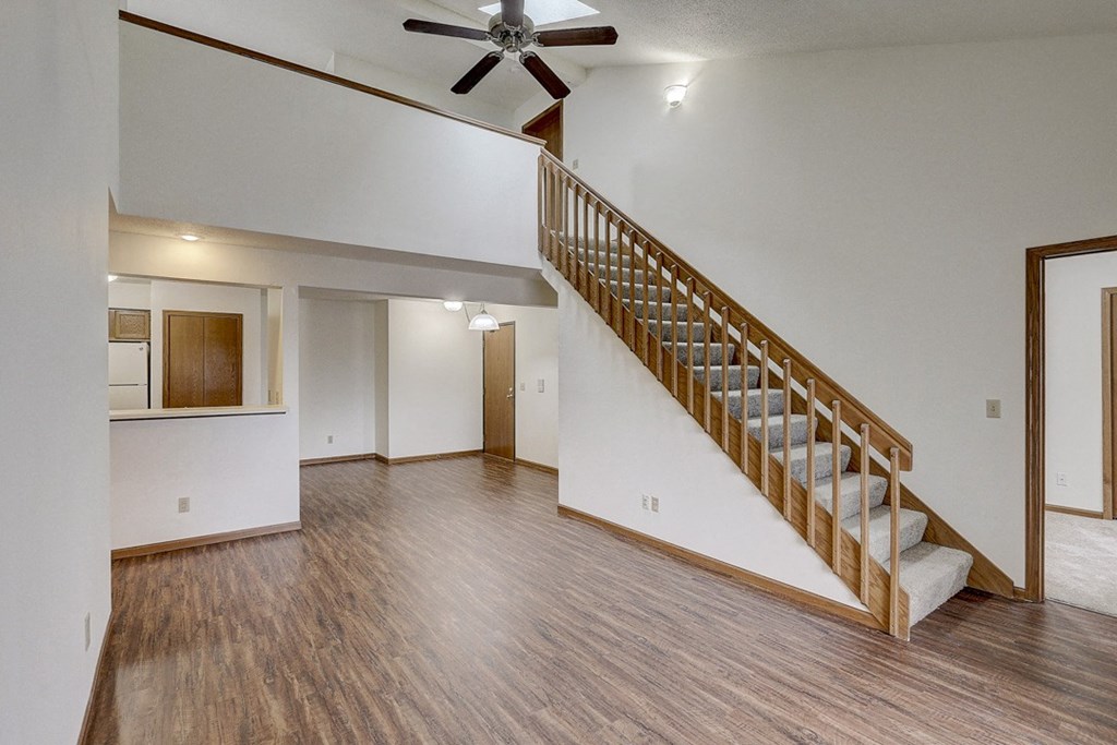 the living room and dining room of an empty house with a staircase