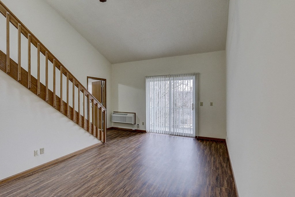 the living room and entryway of an empty house with wood flooring and a