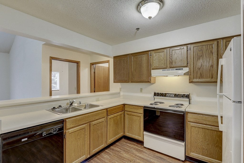 an empty kitchen with wooden cabinets and a stove and a sink