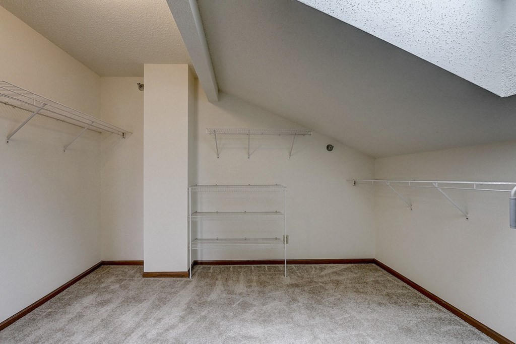 an empty room with white walls and a closet with shelves