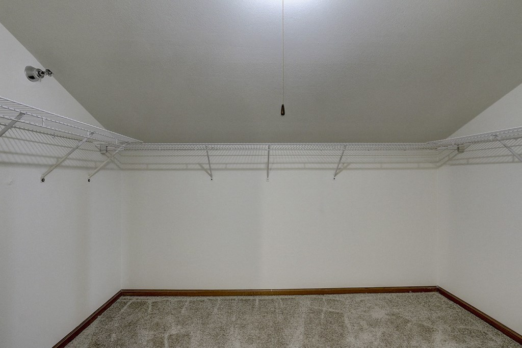 an empty room with white walls and a hanging light on the ceiling