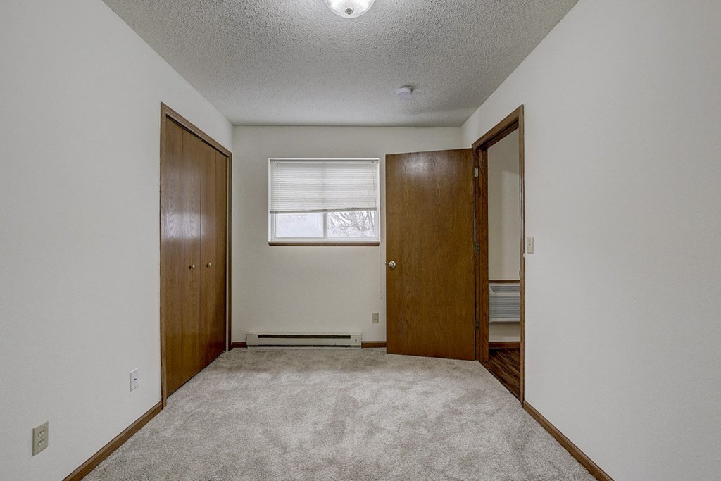 an empty room with a door to a closet and a window
