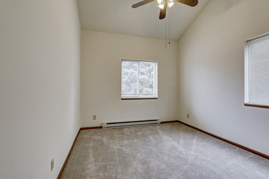 an empty living room with a ceiling fan and a window