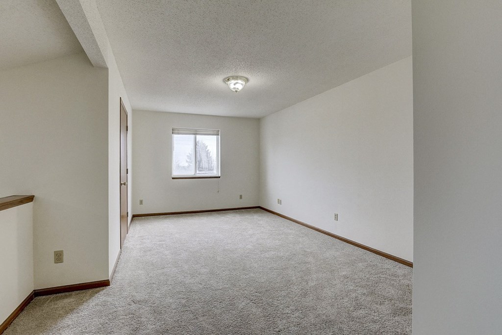 an empty living room with white walls and a window