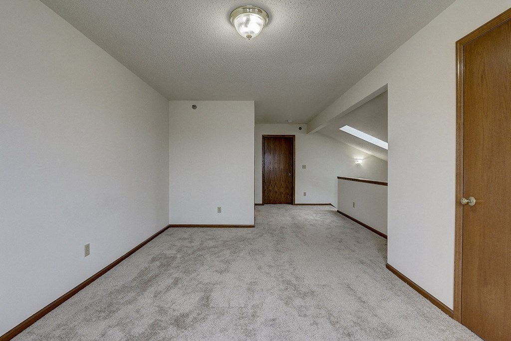 an empty living room with white walls and a wooden door