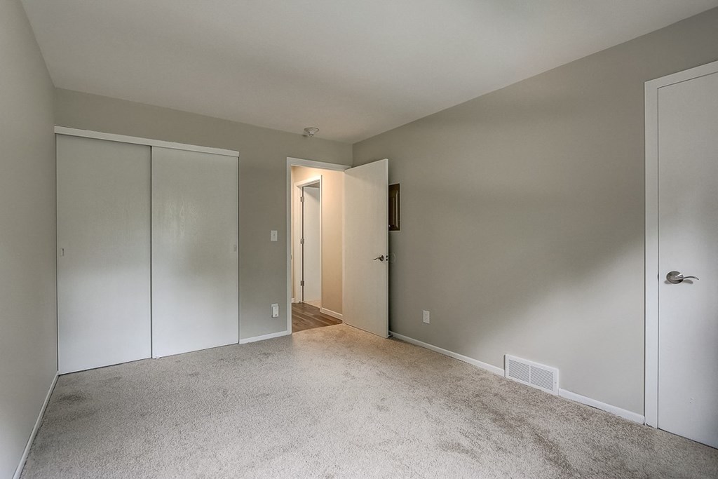 a bedroom with a carpeted floor and a door to a closet