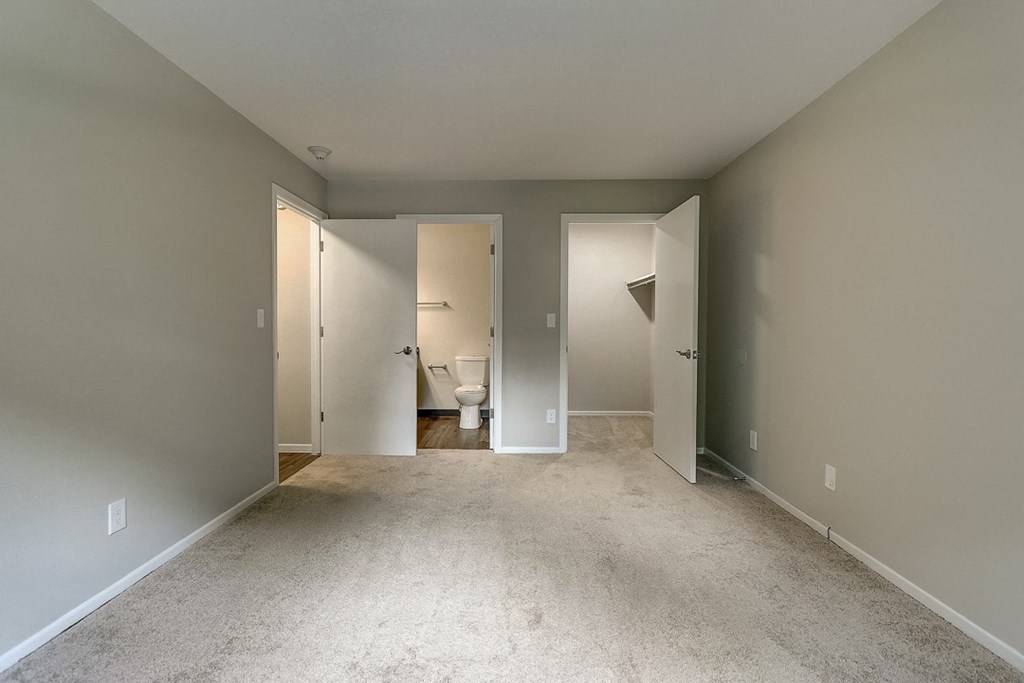 an empty room with a bathroom and a toilet in the distance