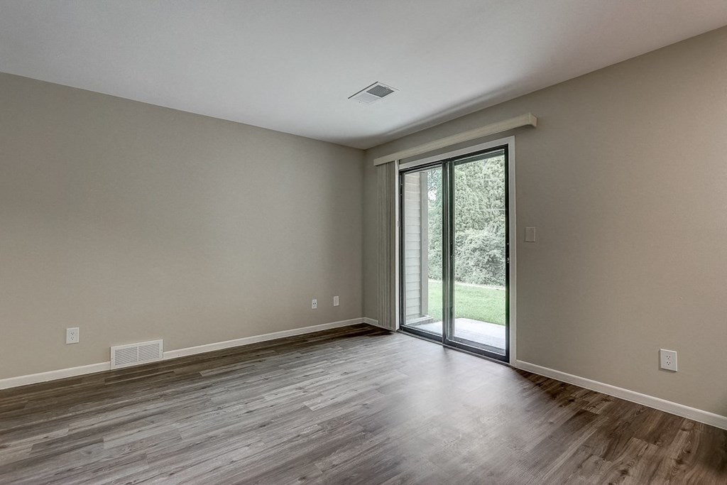 an empty living room with sliding glass doors to a yard