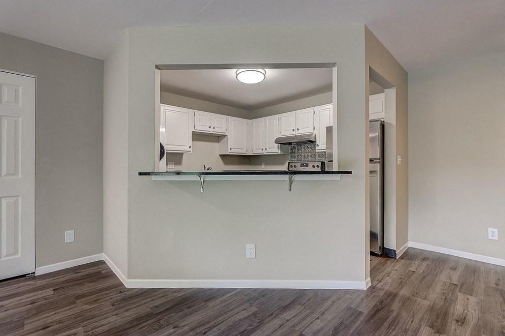 an empty living room with a kitchen and a large mirror