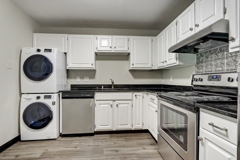 a kitchen with a washer and dryer and white cabinets