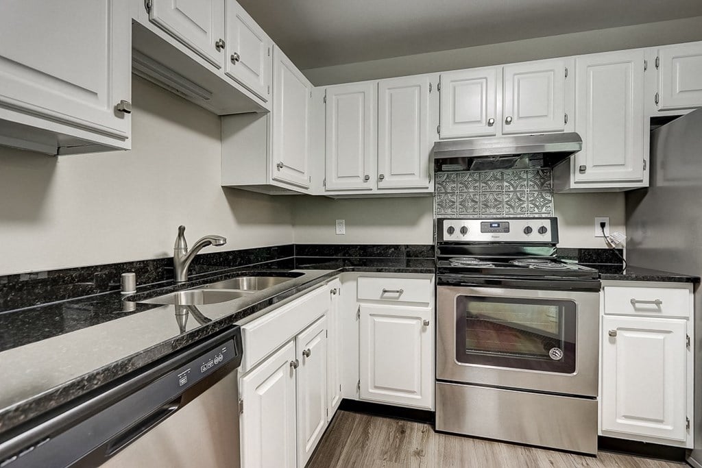 an empty kitchen with white cabinets and stainless steel appliances
