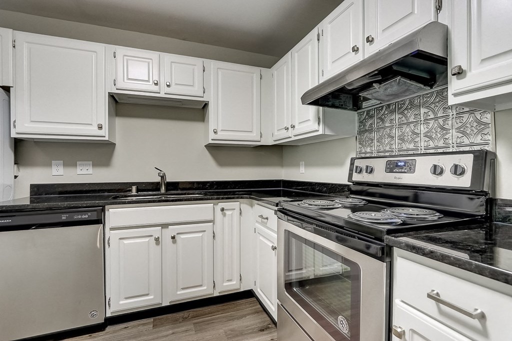 an empty kitchen with white cabinets and black counter tops