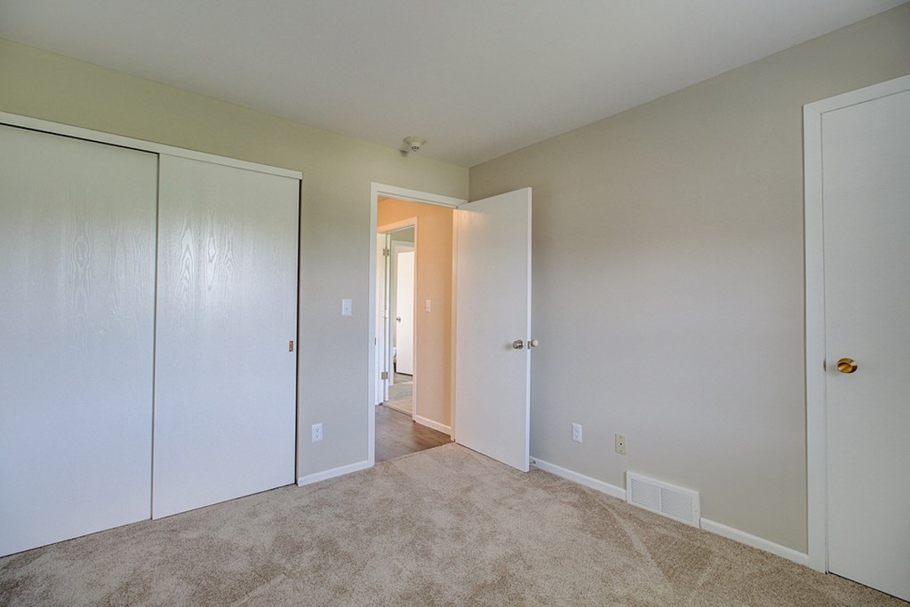 a bedroom with two closets and a carpeted floor
