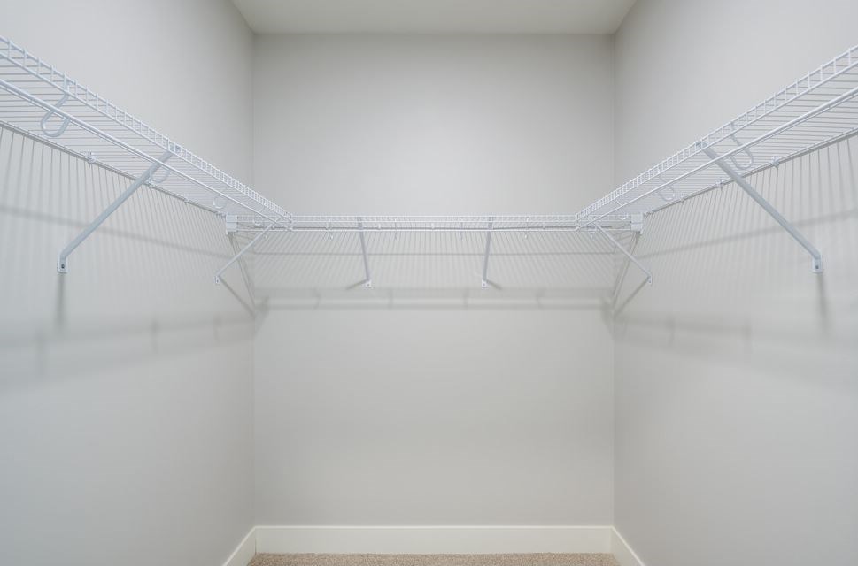 Empty white walk in closet with shelves.