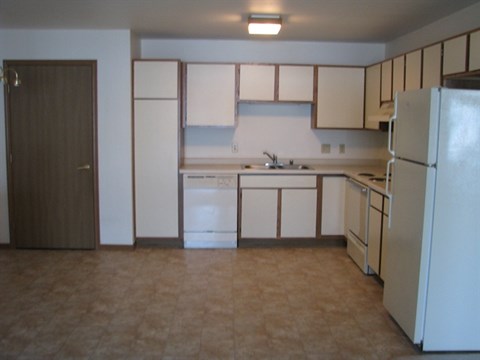 A kitchen with white appliances and brown cabinets.