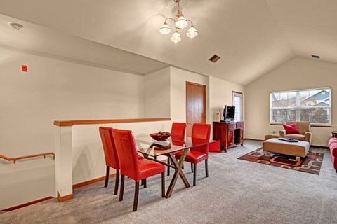 A living room with red chairs and a grey carpet.
