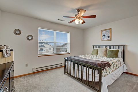 A bedroom with a large bed and a ceiling fan.