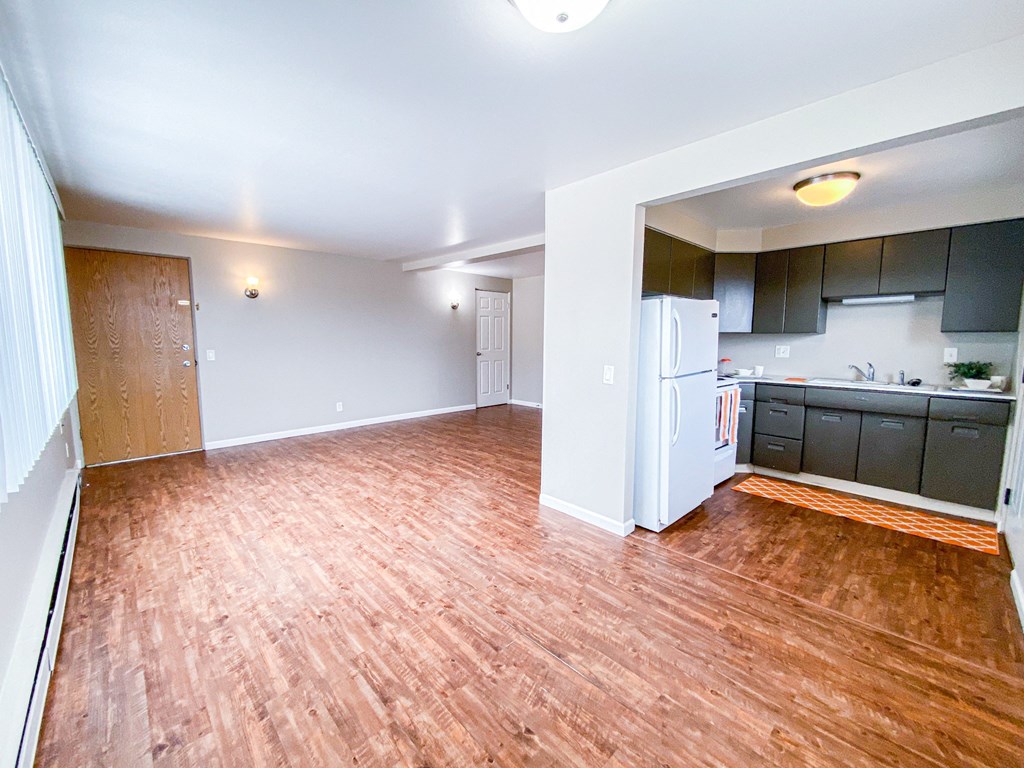 an empty living room and kitchen with a wood floor