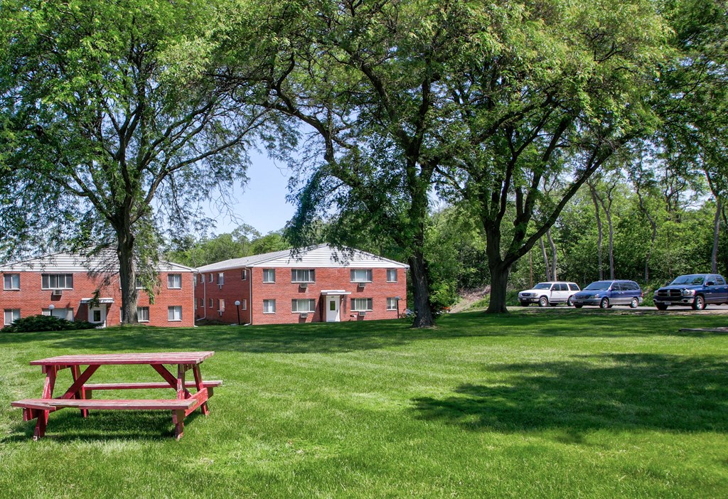 a picnic table in a park in front of a brick building