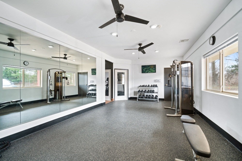a gym with mirrors on the wall and a bench in the middle