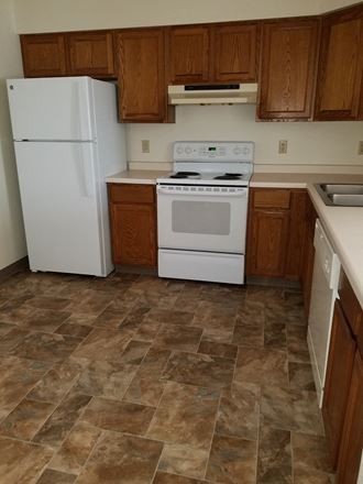 an empty kitchen with a white refrigerator freezer next to a white stove top oven