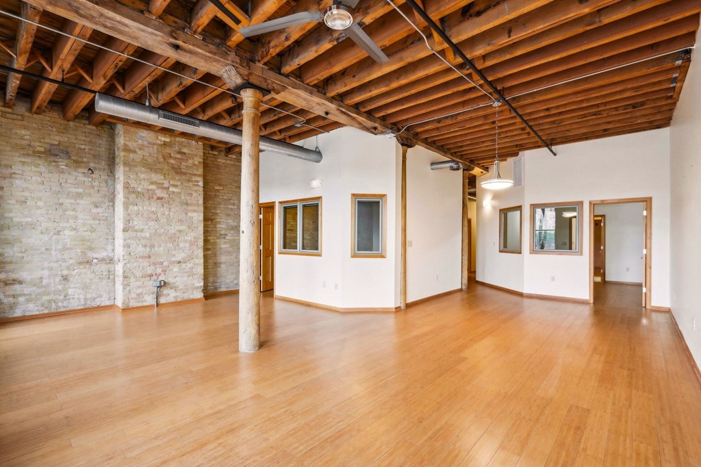 an empty room with wood floors and exposed ceilings