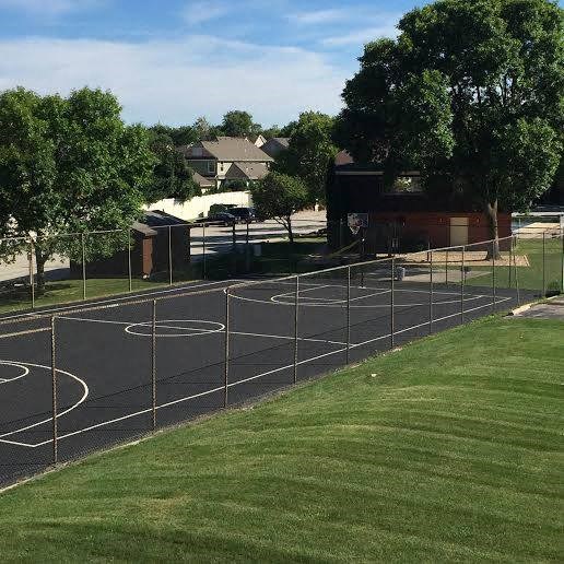 a basketball court in the middle of a grass field