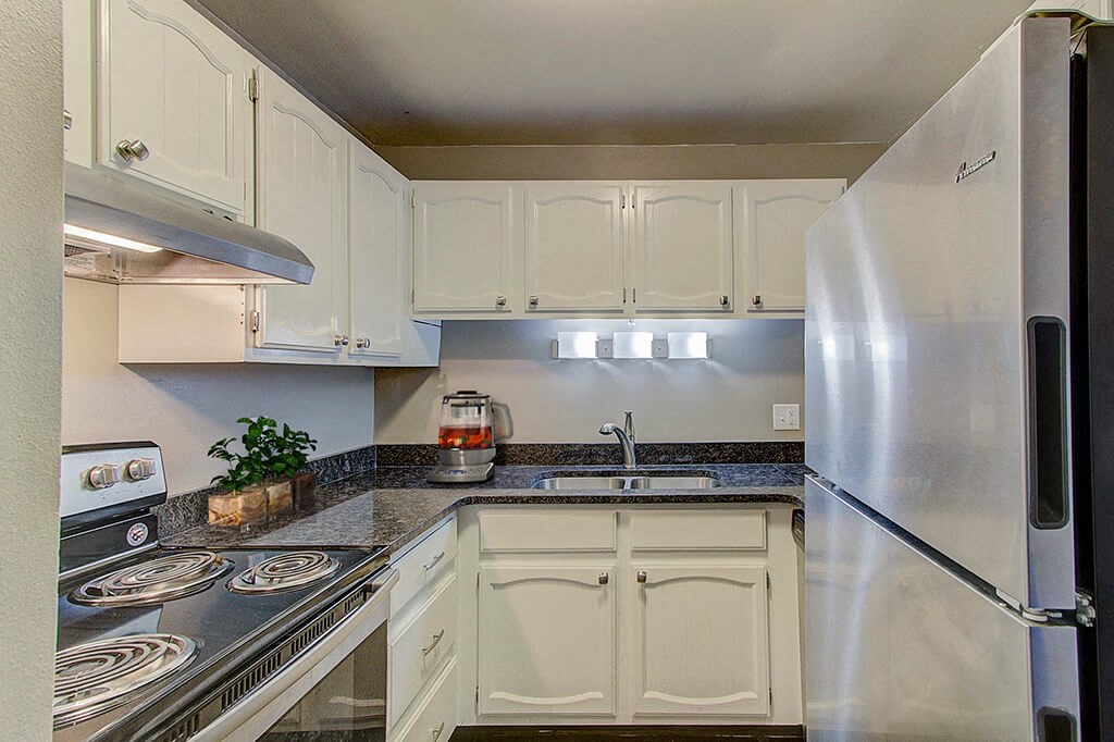 a kitchen with white cabinets and a stainless steel refrigerator