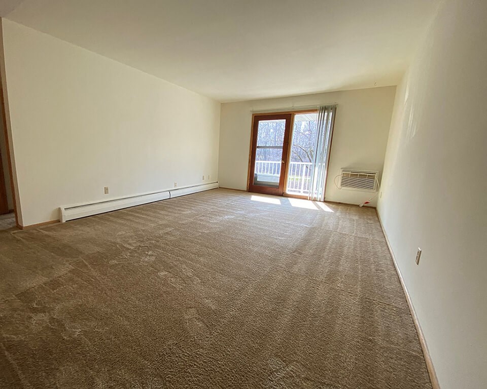 a empty living room with a door to a balcony