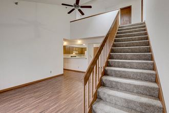 a carpeted staircase in a living room with a ceiling fan