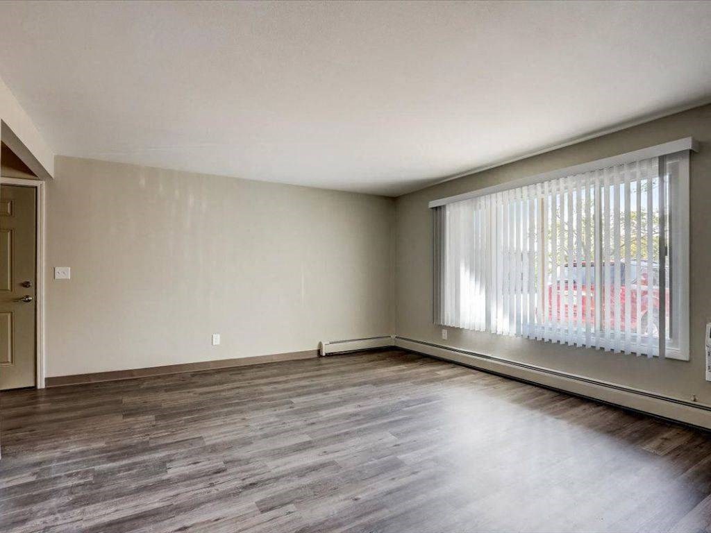 an empty living room with a large window and wood floors