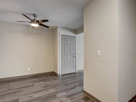 an empty living room with a ceiling fan and a door